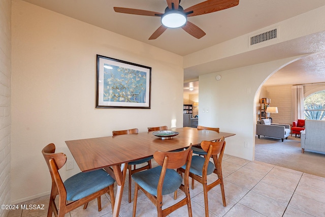 dining room featuring arched walkways, ceiling fan, light tile patterned floors, light colored carpet, and visible vents