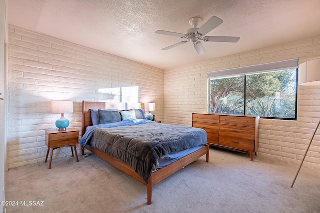 bedroom featuring a textured ceiling, brick wall, ceiling fan, and light colored carpet