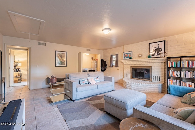 living area with attic access, visible vents, a fireplace, and light tile patterned floors