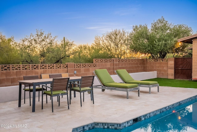 view of patio with outdoor dining area, fence, and a fenced in pool