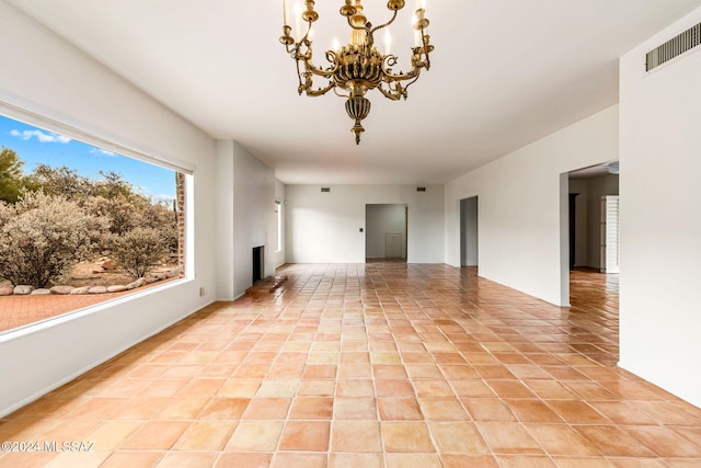 unfurnished living room with a chandelier and light tile patterned floors