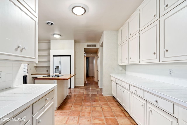 kitchen with white cabinets, tile counters, and backsplash