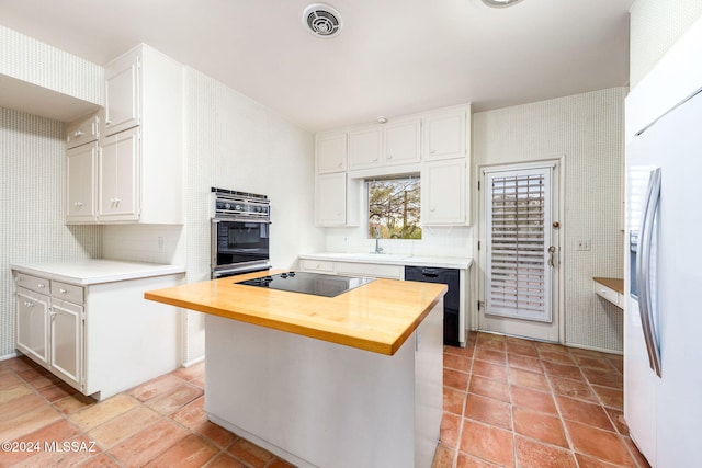 kitchen with black appliances, butcher block countertops, white cabinetry, decorative backsplash, and a center island