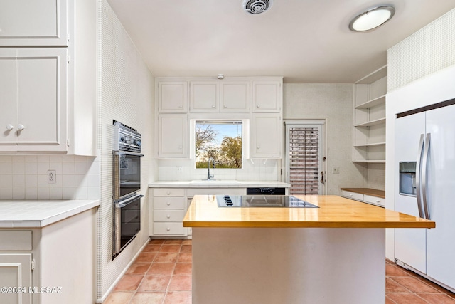 kitchen featuring black appliances, tasteful backsplash, a kitchen island, white cabinetry, and sink