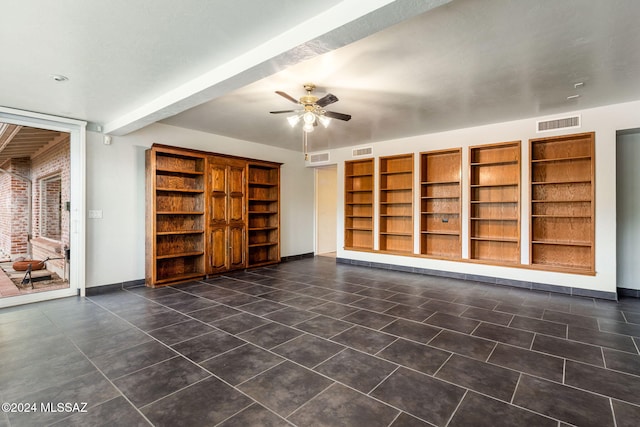 unfurnished living room with built in shelves, ceiling fan, and dark tile patterned floors