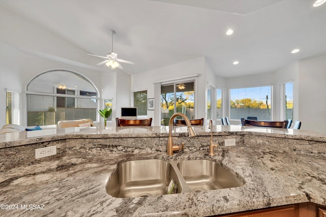 kitchen with light stone countertops, sink, and ceiling fan