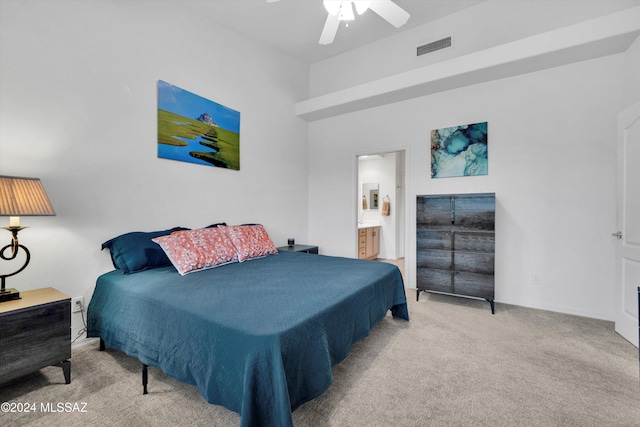 bedroom featuring ceiling fan, ensuite bath, and light carpet