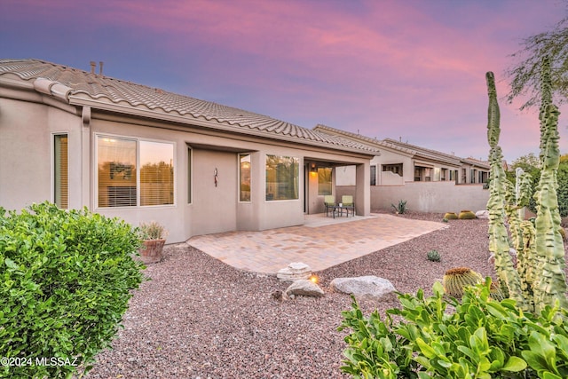 back house at dusk featuring a patio area