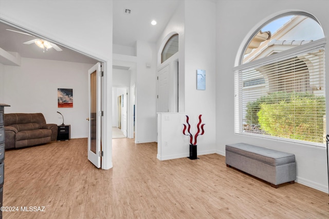 foyer featuring a high ceiling, ceiling fan, and light hardwood / wood-style flooring