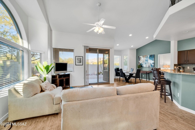 living room featuring light hardwood / wood-style flooring, ceiling fan, and vaulted ceiling