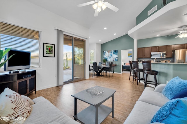 living room featuring ceiling fan, light hardwood / wood-style flooring, and vaulted ceiling