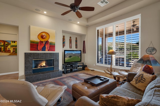 carpeted living room featuring a tiled fireplace and ceiling fan