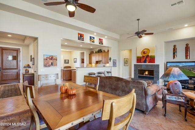 tiled dining space featuring a tiled fireplace and ceiling fan