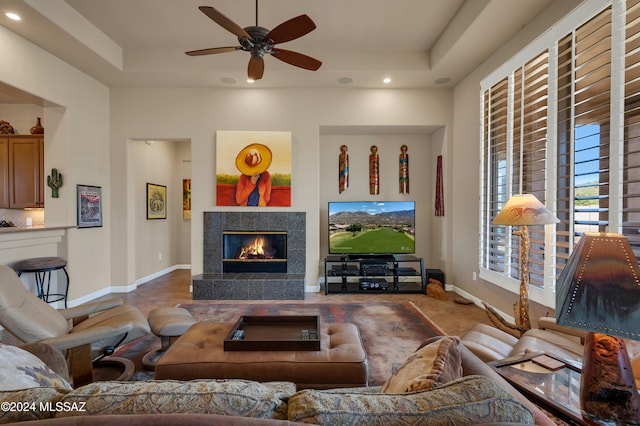 living room featuring ceiling fan, a raised ceiling, and a high end fireplace