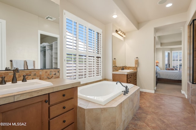 bathroom with vanity, a wealth of natural light, tiled bath, and tile patterned flooring