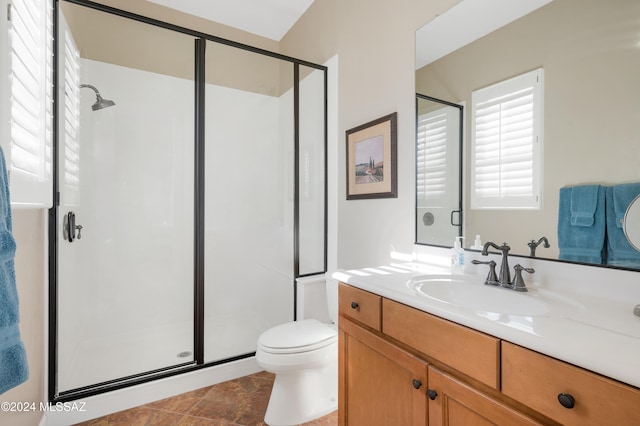 bathroom featuring a shower with door, vanity, toilet, and tile patterned floors