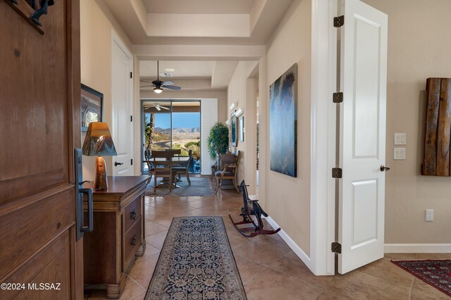 hallway featuring light tile patterned flooring and a raised ceiling