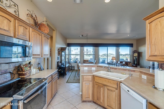 kitchen with pendant lighting, sink, a notable chandelier, kitchen peninsula, and stainless steel appliances