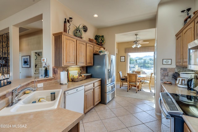 kitchen featuring sink, ceiling fan, decorative backsplash, light tile patterned flooring, and stainless steel appliances