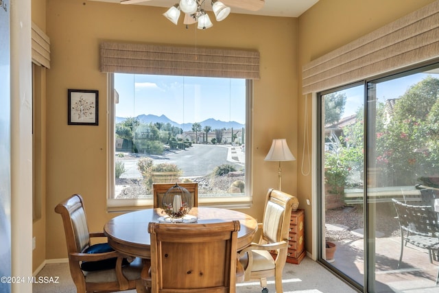 dining area featuring carpet flooring, plenty of natural light, ceiling fan, and a mountain view