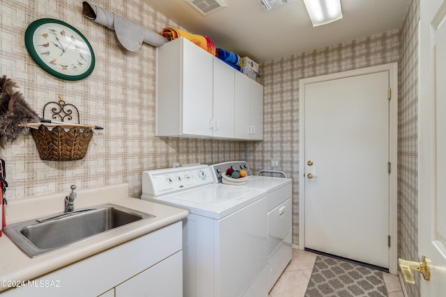 laundry area with cabinets, sink, light tile patterned flooring, and washing machine and clothes dryer