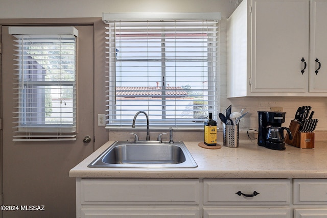 kitchen featuring tasteful backsplash, white cabinetry, sink, and a healthy amount of sunlight