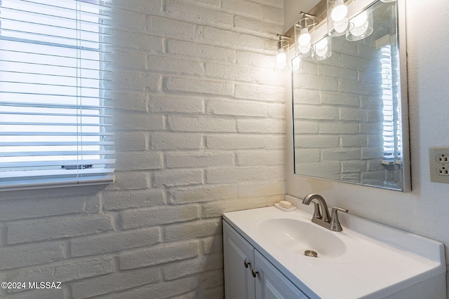 bathroom featuring vanity, a healthy amount of sunlight, and brick wall