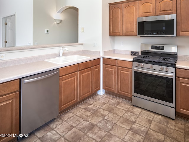 5567 W Dove Loft Dr, Marana, AZ 85658 - kitchen featuring stainless steel appliances, a sink, stone finish flooring, light countertops, and brown cabinets