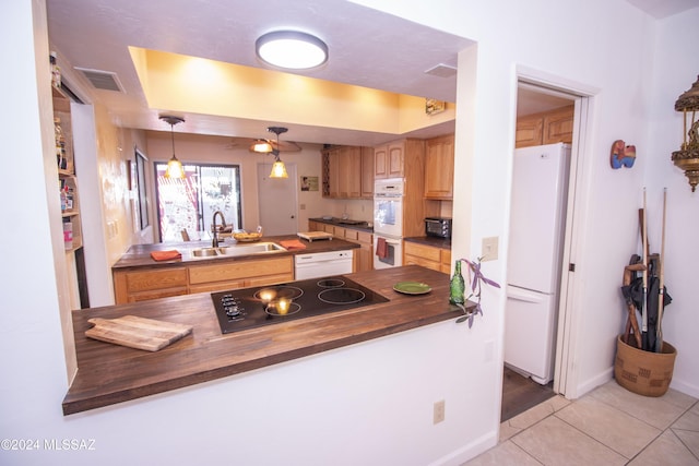 kitchen with wooden counters, white appliances, sink, light tile patterned floors, and hanging light fixtures