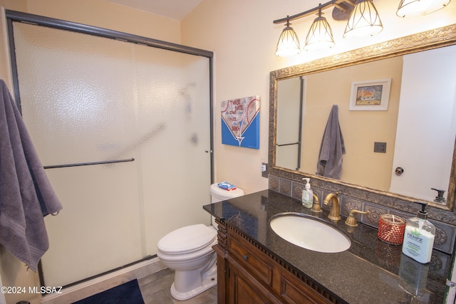 bathroom featuring tile patterned flooring, vanity, toilet, and a shower with shower door