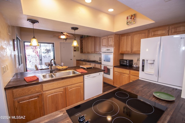 kitchen featuring white appliances, sink, hanging light fixtures, and wooden counters