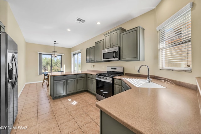 kitchen featuring stainless steel appliances, kitchen peninsula, sink, gray cabinets, and decorative light fixtures