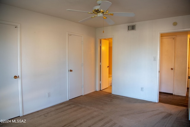 unfurnished bedroom featuring ceiling fan, light colored carpet, and ensuite bathroom