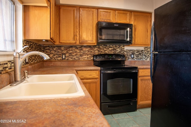 kitchen with decorative backsplash, light tile patterned floors, sink, and black appliances