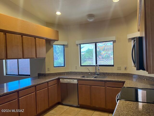 kitchen with light tile patterned floors, dishwasher, kitchen peninsula, and sink