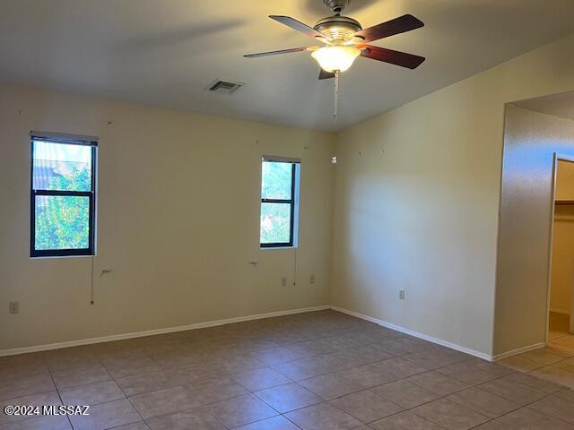 unfurnished room with ceiling fan, a wealth of natural light, and light tile patterned flooring