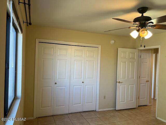 unfurnished bedroom with ceiling fan, light tile patterned flooring, and a closet