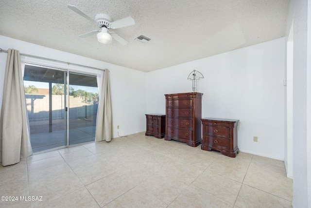 empty room with a textured ceiling, ceiling fan, and light tile patterned flooring