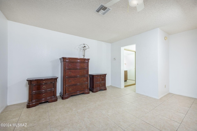 bedroom featuring light tile patterned flooring, a textured ceiling, ceiling fan, and ensuite bath