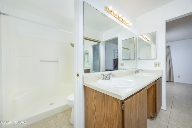 bathroom with tile patterned flooring, vanity, toilet, and a shower