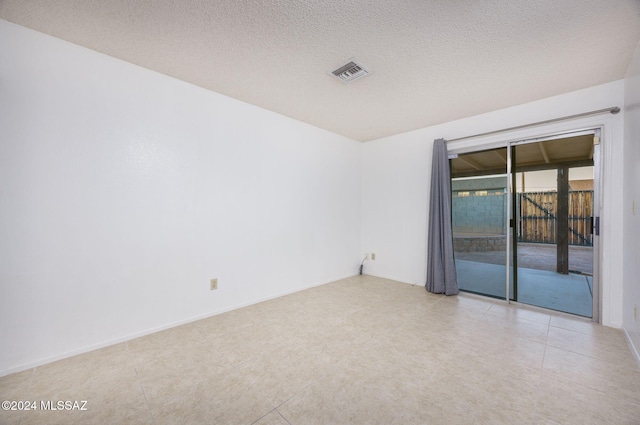 tiled empty room featuring a textured ceiling