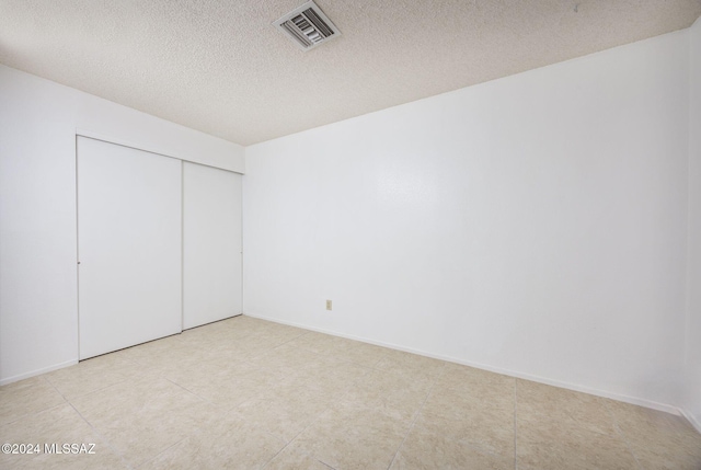 unfurnished bedroom featuring a textured ceiling and a closet