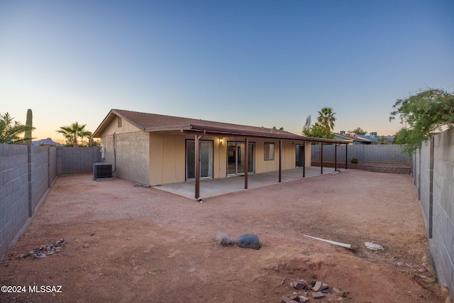 back house at dusk featuring a patio and cooling unit