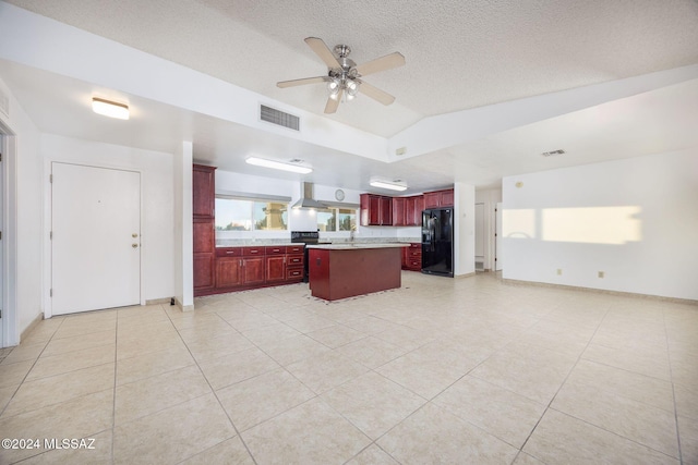 kitchen with black fridge, light tile patterned floors, vaulted ceiling, ceiling fan, and a center island