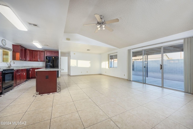 kitchen with black appliances, light tile patterned flooring, a kitchen island, a breakfast bar, and lofted ceiling