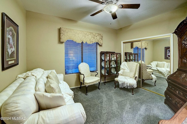 living area featuring dark colored carpet, ceiling fan, and a textured ceiling