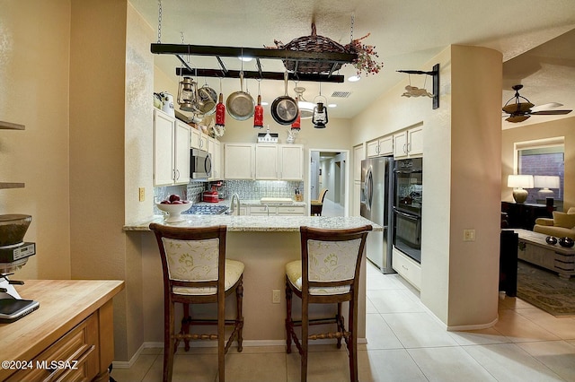 kitchen with a kitchen bar, appliances with stainless steel finishes, tasteful backsplash, ceiling fan, and sink