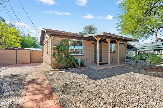 view of front facade with a patio area and a storage shed