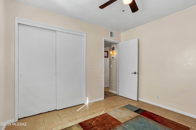 unfurnished bedroom with ceiling fan, light tile patterned flooring, and a closet