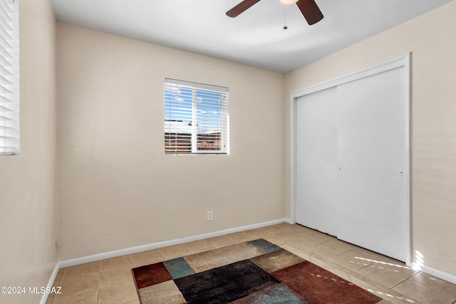 unfurnished bedroom featuring ceiling fan, a closet, and light tile patterned floors